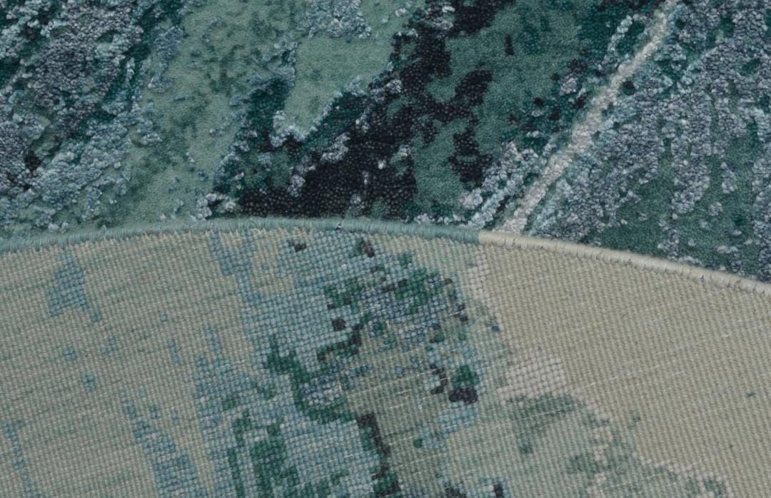 Edge of a round teal rug showing the face and the back of the weave