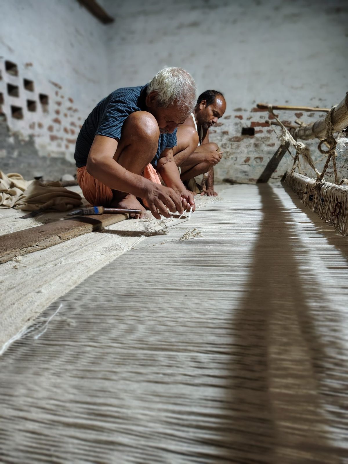Two weavers working at a horizontal loom